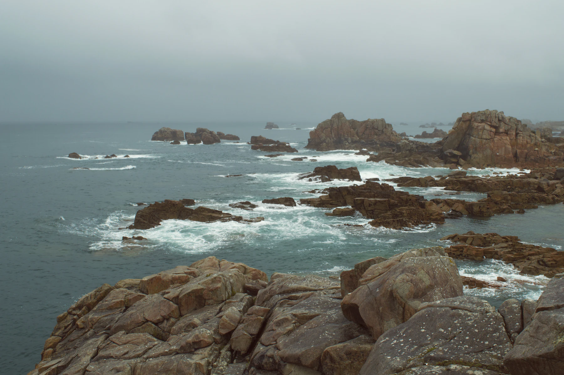 A rugged rocky coastline with sea stacks and breaking surf