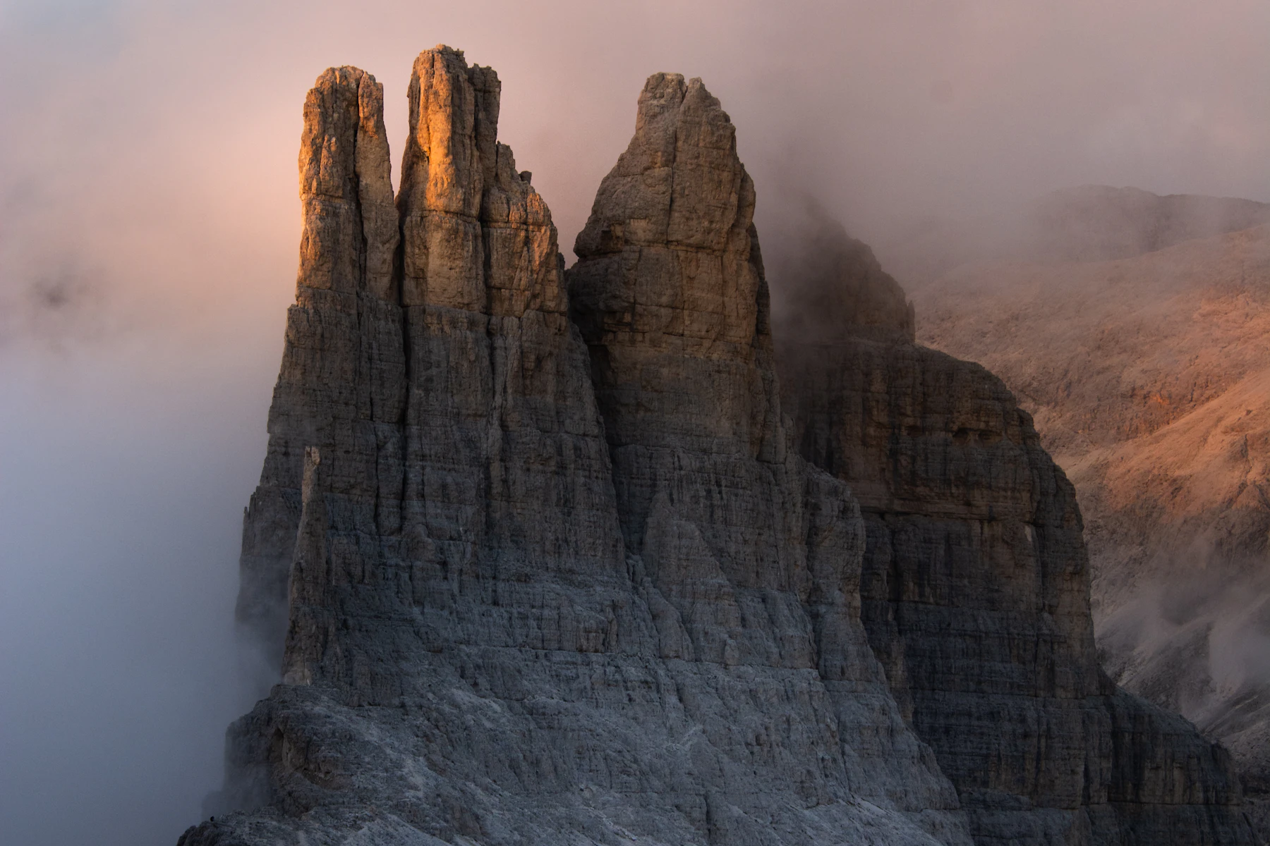 Steep rock spires rising from a mist-filled Dolomite valley